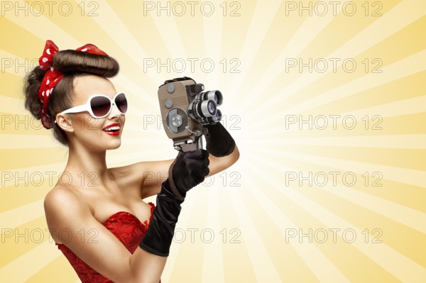 Glamorous pin up girl shooting a film with an old retro cinema 8mm camera on a colourful abstract cartoon style background