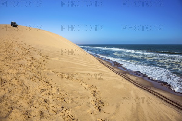 Ocean surf with foamy waves. Atlantic coast of Walvis Bay, Namibia, south of Africa. Dangerous jeep - safari through the huge sand dunes. The concept of extreme and exotic tourism, Africa