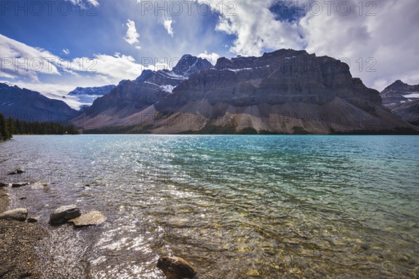 The cold waters of the lake surrounded by scenic Canadian Rocky Mountains. Azure Bow Lake in Banff National Park