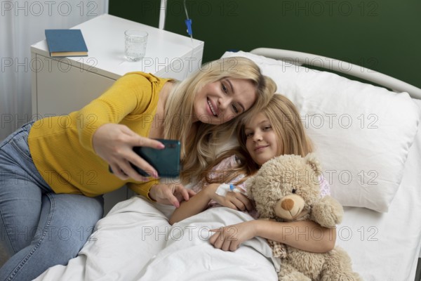 A heartwarming selfie captures a loving mother and daughter sharing a joyful moment in a hopeful hospital room