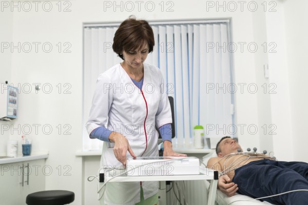 Medical equipment for electrocardiogram. Doctors doing ECG test on male patient. Diagnostic heart disease heart attack, tachycardia. Electrocardiography procedure. Cardiologist doing check-up test