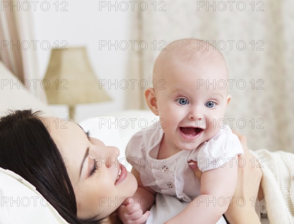 Happy smiling mother with six month old baby girl indoor