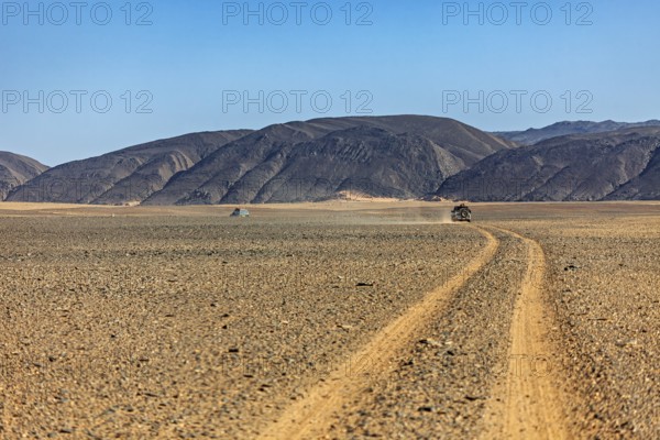 Dusty desert road leads through barren landscape with mountains, By off-road vehicle through the endless landscape of the Sahara desert in Algeria