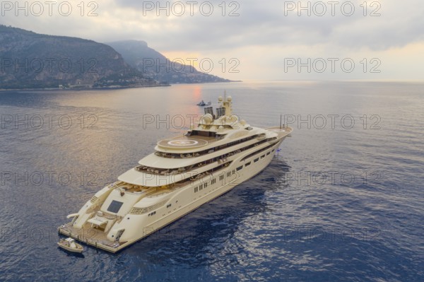 Aerial view of 156-metre superyacht DILBAR, delivered in 2016 by the Lürssen Yachts shipyard to Russian oligarch Alisher Usmanov Alisher Usmanov, General Director of Gazprominvestholding, co-owner of Metalloinwest, owner of publishing house Kommersant. Largest yacht in the world by volume. Currently under arrest at the shipyard due to sanctions against Russia, here at anchor at sunrise on the Cote d'Azur, Alpes-Maritimes, Provence-Alpes-Cote d'Azur, Southern France, France, Mediterranean Sea, Europe