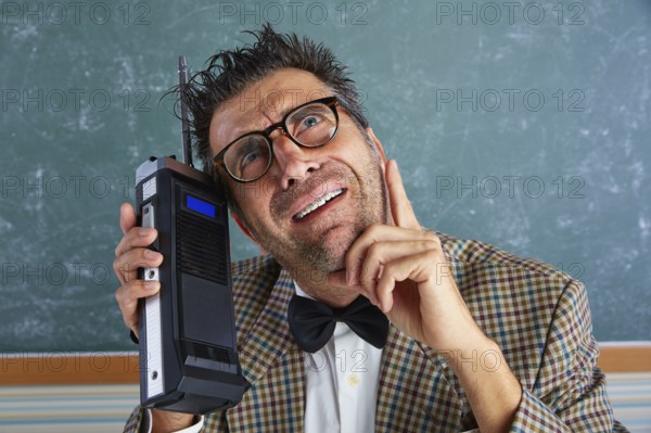 Nerd silly private investigator with retro walkie talkie on teacher balckboard