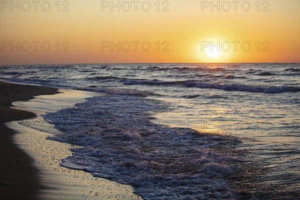 Beautiful sunset over the sea. Red sun and waves