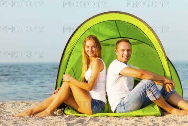Happy young couple camping on the beach. Summertime