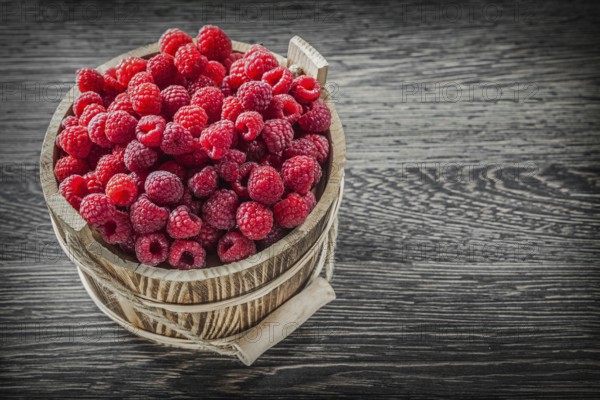 Red raspberry in bucket on vintage wooden board