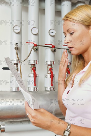 A young woman with a billing of heating costs for heating. In the boiler room. Austria