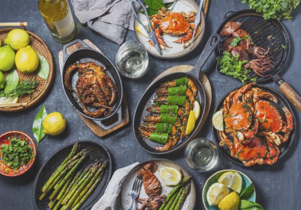 Food, Food, Set table with seafood dishes, cooked crabs, tiger shrimps, grilled octopus and squids on cast iron grilled pans and plates, White wine. Toned photo. Top view