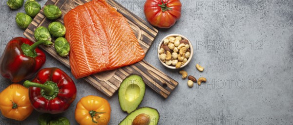 Fresh raw salmon fillet on wooden cutting board, organic bio vegetables and nuts on rustic stone grey background top view. Ingredients full of vitamins for healthy diet and nutrition, space for text, food photography, food photography