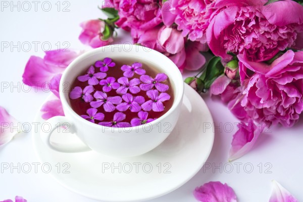Creative layout with pink peonies flowers and cup of tea on bright table. Spring Seasonal valentine, woman, mother, 8 march holiday, romance breakfast. Stylish blogger. Greeting card. Invitation. Blog post
