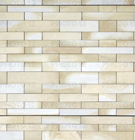 Full frame image of a wall made of large flat blocks of textured yellow light brown york stone in different sized rows