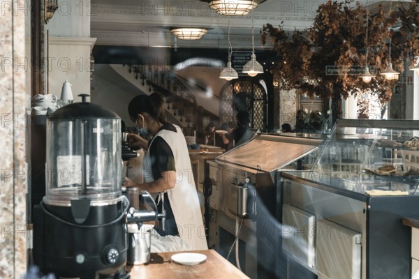 Madrid, Spain, October 11, 2020: View through the window of a cafe with vintage decoration and a waitress preparing coffee, Europe