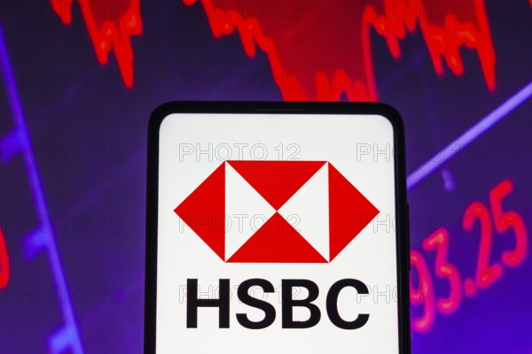 In this photo illustration the HSBC logo seen displayed on a smartphone screen, with graphic representation of the stock market in the background