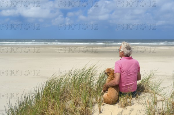 Man sitting with the dog at the beach
