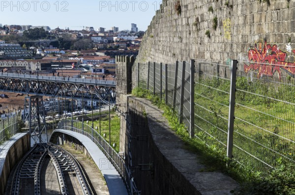 View of the tracks of the funicular railway Funicular dos Guindais and the bridge Ponte Luis (Luiz) I., on the right city wall Muralha Fernandina, in the city of Porto, Portugal, Europe