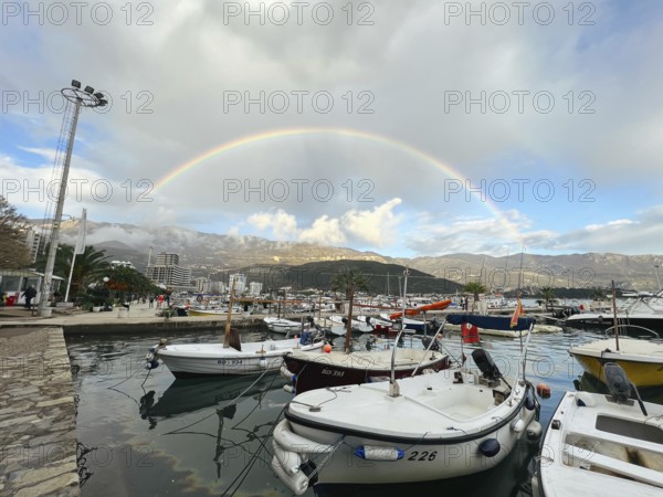 Yachts moored at the pier against the backdrop of a rainbow over the mountains.