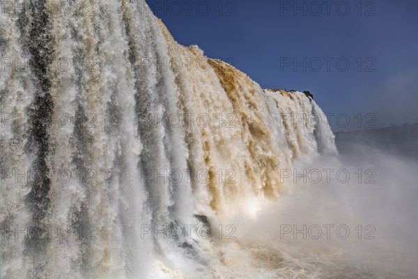 Close-up view of powerful Iguazu Falls in different colors and with blue sky