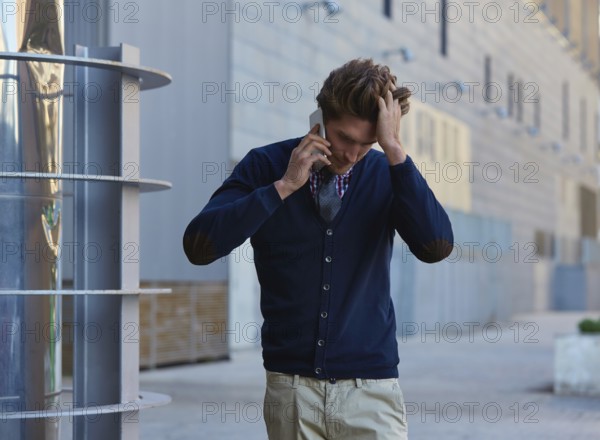 Young businessman talking smartphone phone walking on the street