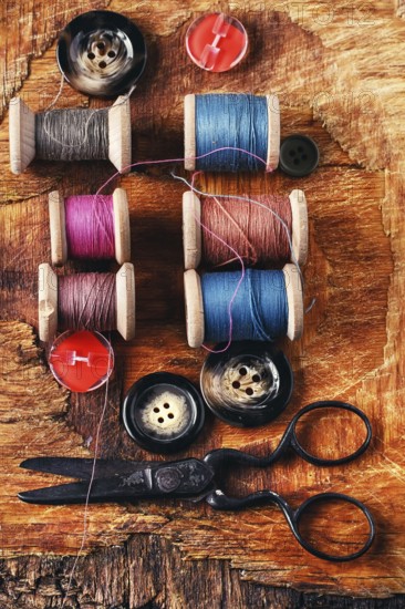 Six antiquated sewing threads and buttons on retro background