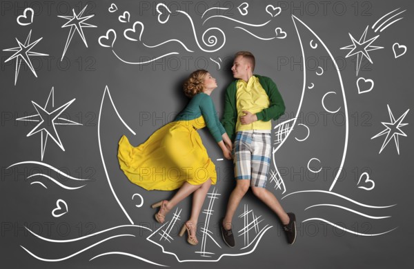Happy valentines love story concept of a romantic couple swimming on the moon boat, holding hands and kissing against chalk drawings background of a night sky