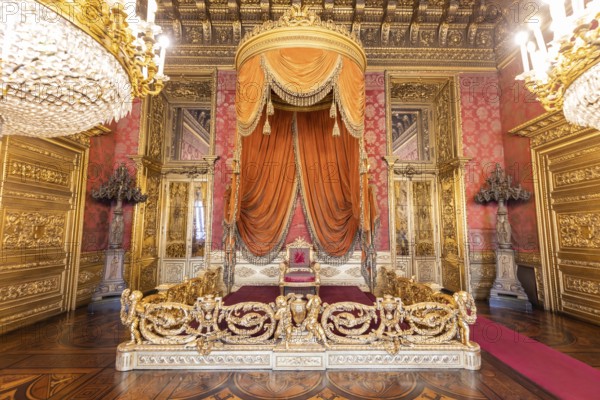 Turin, Italy, Circa August 2021: old throne room interior with chair in luxury palace. Red and gold antique Baroque style, Savoia Royal Palace, Europe