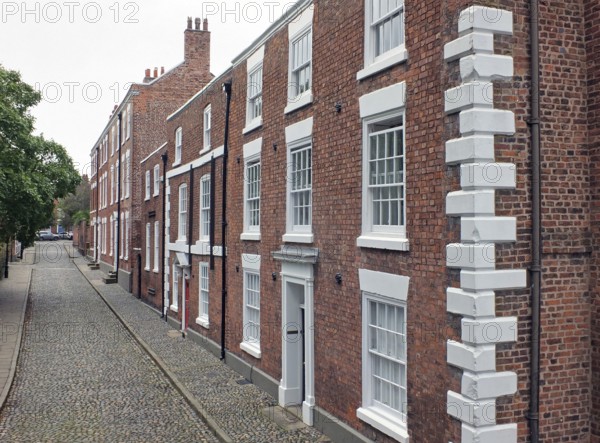 A street of elegant large brick 19th century houses in chester england with cobblestone pavement and road