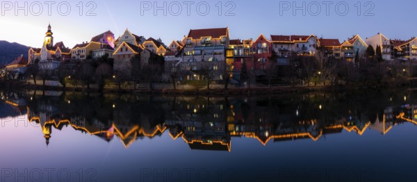 Christmas illuminated house facade of Frohnleiten reflected in the river Mur, panoramic shot, blue hour, Frohnleiten, Styria, Austria, Europe