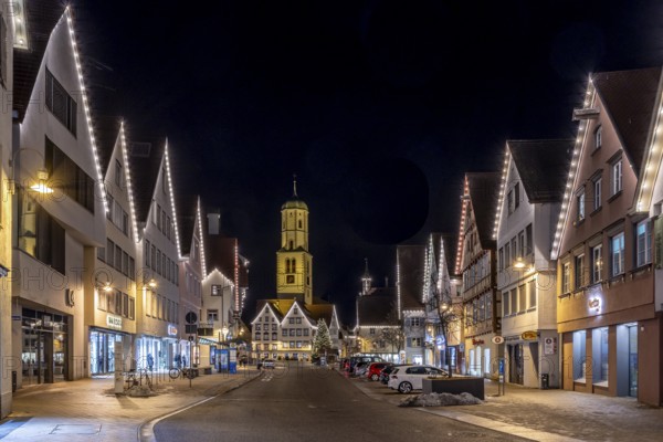 Night photo of historic buildings around the market square with Christmas tree and Christmas lights around the roofs of the buildings and in the background the steeple of the parish church of St Martin, Biberach an der Riß, Upper Swabia, Baden-Württemberg, Germany, Europe