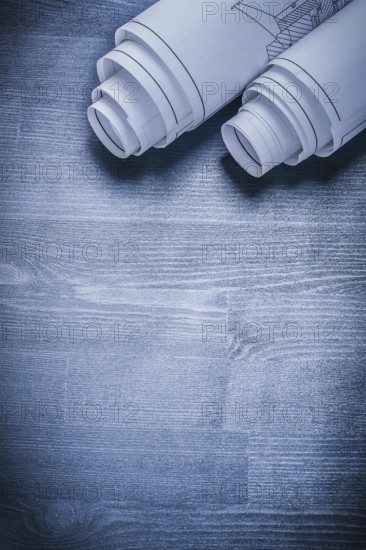 Vertical view two rolled white blueprints