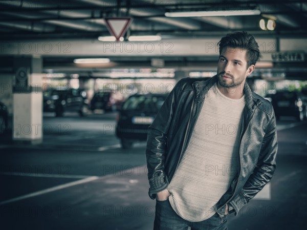 Handsome muscular man in casual clothing on background of parking