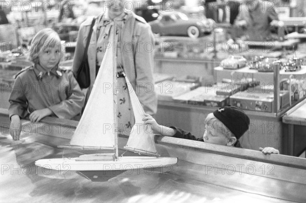Toys in the 1950s. At a department store a boy is curious of the nice sailboat model floating in the water and touches it. Sweden 1954 Kristoffersson ref 2A-33