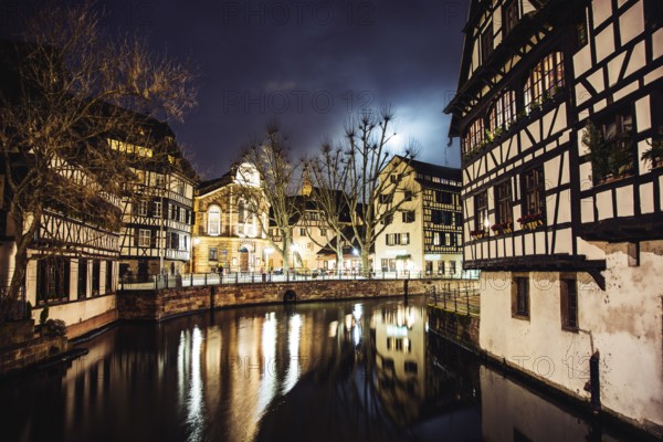 Scenic view View on river in Strasbourg, France at night. Romantic lights reflecting on the water and traditional houses and buildings all around