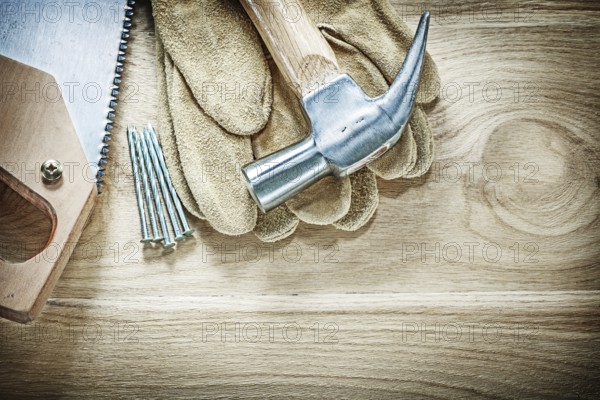 Set of claw hammer safety gloves handsaw nails on wooden board construction concept