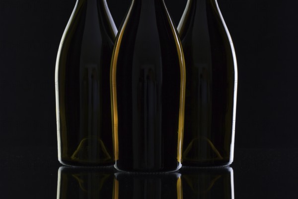 Three different bottles of wine on the black glass