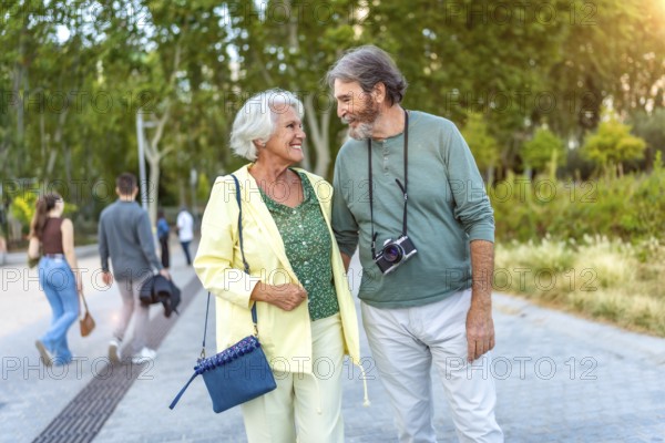 Three quarter length photo of a caucasian cute senior couple walking together along a city park