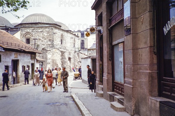 People walking along street of shops, next to domes of Brusa Bezistan museum, Sarajevo, Bosnia and Herzegovina, former Yugoslavia, Europe 1960, Europe