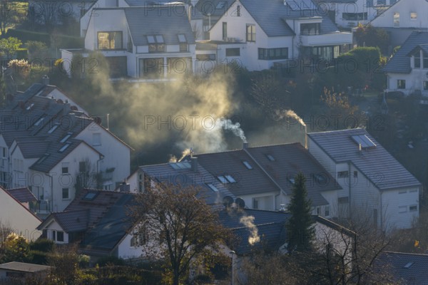 Symbolic image, pollution, global warming, climate change, smoke from chimneys in a residential area with modern architecture and autumnal atmosphere, Baden-Württemberg, Germany, Europe