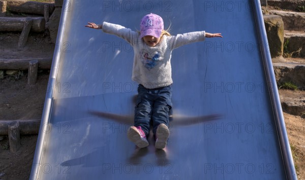 Little girl, 3 years, blonde, baseball cap, logo NYY New York Yankees, jumper, Disney, Elsa, Ice Queen, slides on slide, playground, Stuttgart, Baden-Württemberg, Germany, Europe