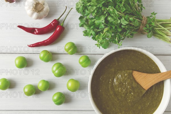 Tkemali sauce, traditional Georgian cuisine, green cherry plum, with ingredients for sauce, cilantro, mint, hot pepper, garlic, on a white wooden table, close-up, rustic, food background, no people, selective focus, sauce, green sauce, tkemali, georgian cuisine, homemade