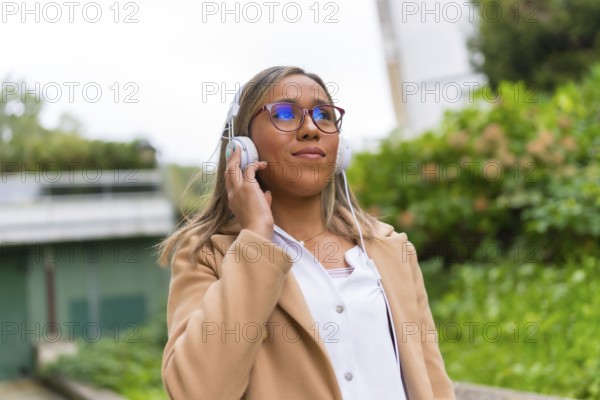 Latin woman listening to music walking along the street in a residential area