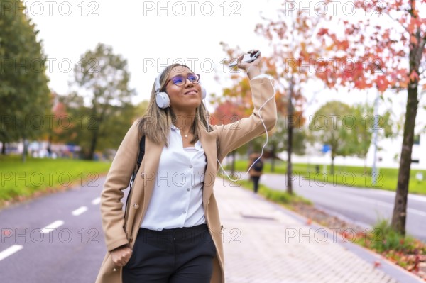 Latin woman wearing casual business clothes dancing while listening to music in the city