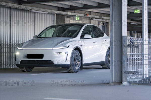 White electric car with modern lines and LED lights in a multi-storey car park, Tesla New Model Y Juniper, Calw, Germany, Europe