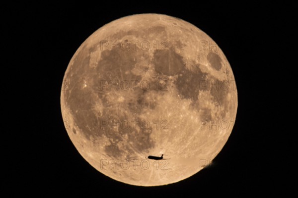 An aeroplane flies past in front of the so-called super full moon in August, Frankfurt, Hesse, Germany, Europe