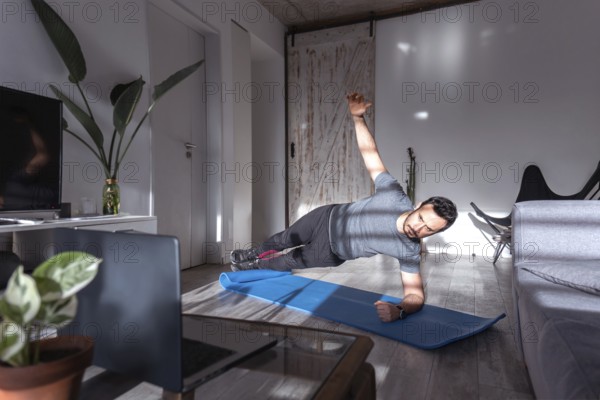 Latin man at home training side plank. Online training class