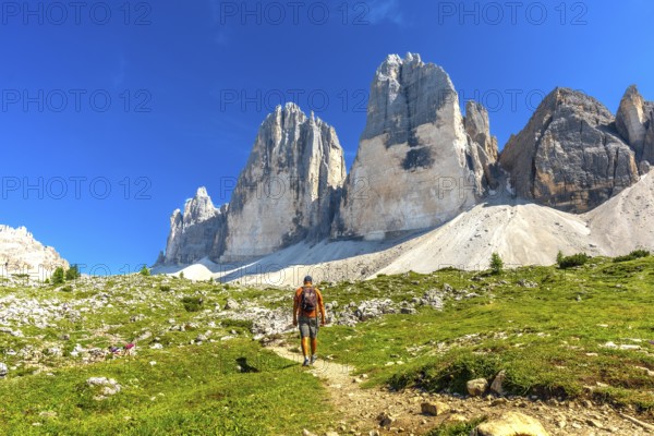 Tourist enjoying a summer hike on a scenic trail leading to the majestic tre cime di lavaredo peaks in the dolomites, italy
