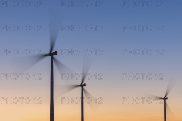 Three wind turbines in front of a colourful sky at sunset, moving quickly in the wind, Rems Valley, Baden-Württemberg, Germany, Europe