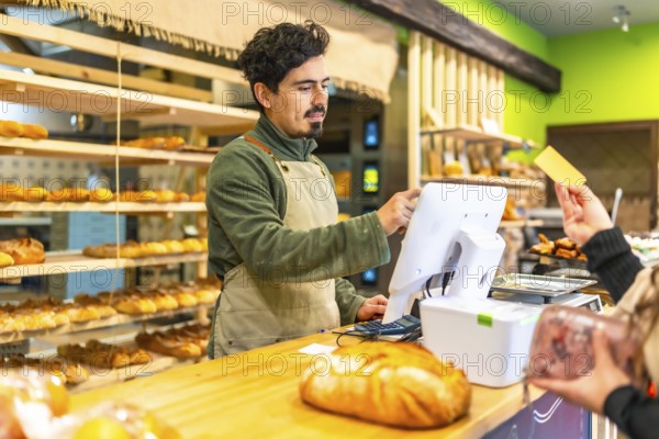 Woman waiting to check out and pay with credit card in an artisan bakery