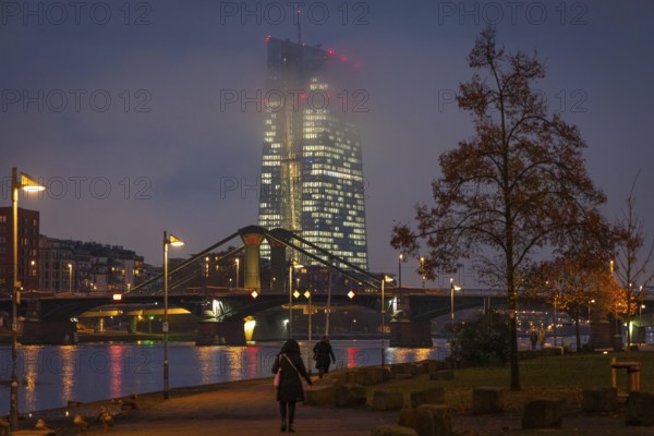 Low clouds envelop the illuminated European Central Bank (ECB) in Frankfurt am Main in the evening. Frankfurt am Main, Mainufer, Hesse, Germany, Europe